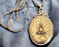 "Description: Beautiful vintage gold filled oval locket that is hand engraved with a whimsical floral and swirling vine design, the raised emblem of the Royal Canadian Mounted Police, and crowned with a fancy filigree top and a decorative fanned bale. This circa mid century locket has both a wonderful etched design and the colored enamel to make it an eye catching necklace indeed. It was most likely once owned by someone who was married to, or served themselves, as a Mountie in Canada. The locke Canadian Mounted Police, Maple Leaf Wreath, Mounted Police, Oval Locket, Gold Text, Photo Pendant, Vine Design, Leaf Wreath, Locket Necklace