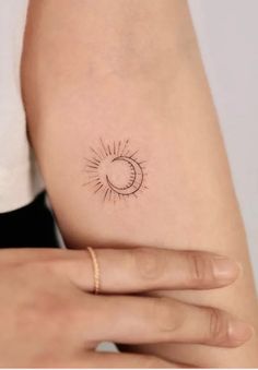 a woman's arm with a small sun and moon tattoo on it