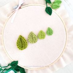 three green crocheted leaves on a white hoop