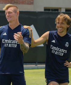 two soccer players standing next to each other with their arms around one another and smiling