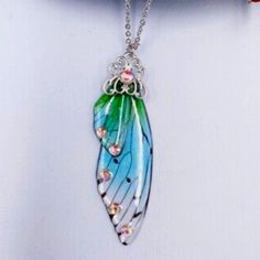 a necklace with a blue and green feather hanging from it's side