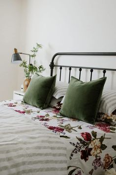 a bed with two pillows on it and some plants in the corner next to it