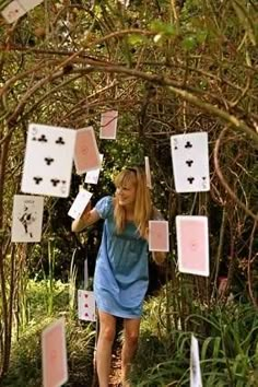 a woman walking through a forest with lots of cards stuck to the trees