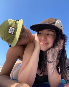 two young women laying on top of a beach next to each other