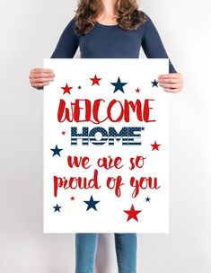 a woman holding up a sign that says welcome home we are so proud of you