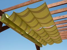 a wooden structure with green striped awnings on the top and bottom, against a blue sky