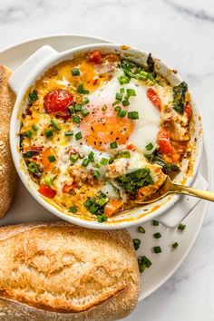 an egg in a bowl with bread on the side next to it and a baguette