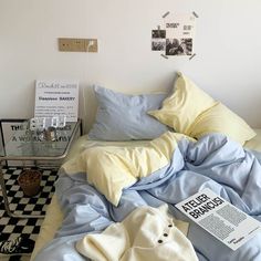 an unmade bed with blue sheets and yellow blankets on it, next to a black and white checkered floor