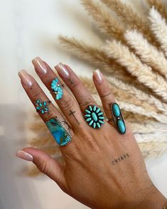 a woman's hand with several rings on her fingers and two flowers in the middle