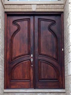 a large wooden door sitting on the side of a brick wall next to a window