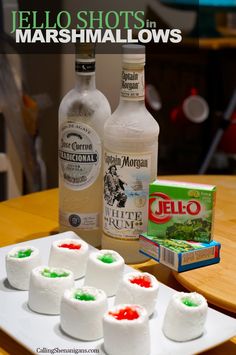 marshmallows are arranged on a white plate with jello shots in the background