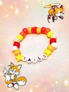 a beaded bracelet with an orange and white cat on it, sitting next to a toy