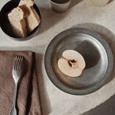 an apple slice is on a plate next to some silverware and two cups with milk in them