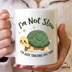 a woman is holding a coffee mug with a turtle on it's side and the words i'm not slow, i'm just taking my time