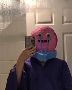 a person taking a selfie in front of a mirror wearing a pink doughnut mask