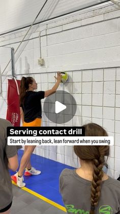 two girls are doing something on the wall with one girl holding a tennis racket