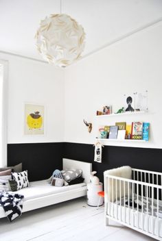 a baby's room with black paint and white furniture, including a crib