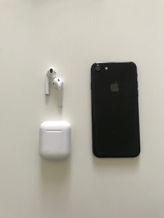 an apple phone, ear buds and headphones are on the table next to each other