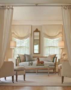 a living room with couches, chairs and a mirror on the wall in front of two windows