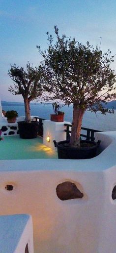 an outdoor hot tub with potted plants and candles on the edge at night time