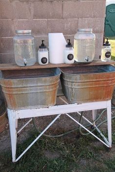 two large metal buckets sitting on top of a table next to jars and containers