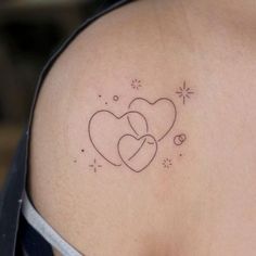 two hearts tattoo on the back of a woman's left shoulder and arm, with stars in the background