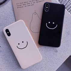 two iphone cases sitting on top of a table next to each other with faces drawn on them