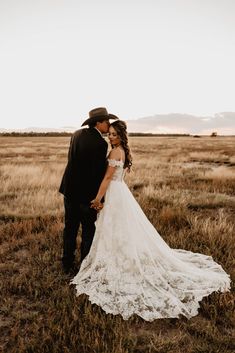 a bride and groom standing in the middle of a field