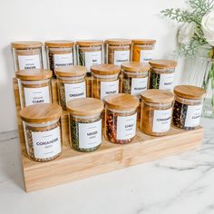 twelve jars of spices sit on a wooden tray