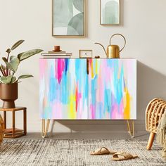 a colorful painted cabinet in the corner of a room next to a chair and potted plant