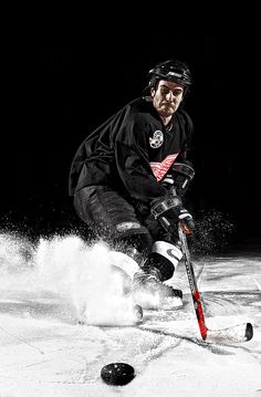 a hockey player is kicking up snow while playing