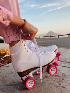 a person wearing white roller skates with pink wheels and laces on their feet