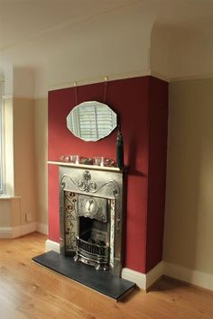 a living room with a fire place next to a large mirror on the wall and wooden floors