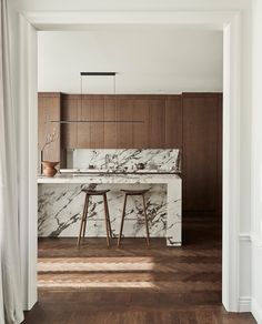 an open kitchen with marble counter tops and stools