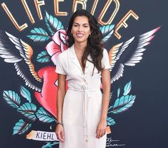 a woman standing on a red carpet wearing a white dress and smiling at the camera