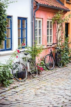 two bikes parked next to each other on a cobblestone street in front of colorful buildings