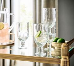 there are many glasses on the table with lemons and limes in front of them