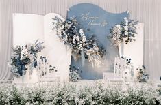 an outdoor ceremony setup with blue and white flowers in vases on the back wall