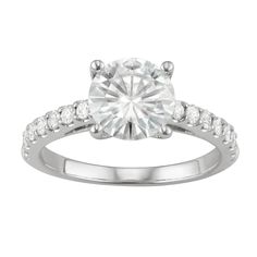 a white gold engagement ring with diamonds on the band and a round cut diamond in the center