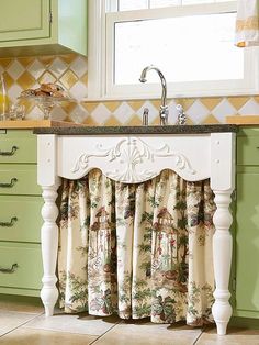 a kitchen sink sitting under a window next to a counter top with curtains on it