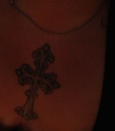 a cross tattoo on the back of a woman's chest