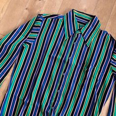 "This piece is a vintage men's striped long sleeve button up shirt from the 1980s. This collared shirt has a knit style multicolour fabric in great colours.  -Made in Taiwan, Bad Berma -100% Nylon  -One small stain on the left shoulder Tag Size: Medium *refer to measurements for true fit* Pit to Pit: 21\" Length: 26\" Please also assess the photos and measurements carefully using your own personal judgement as we do not accept returns. Keep in mind that this is a piece of vintage clothing that may hold a residual scent from its past. While we wash all of the clothing we sell (except for certain items which are steam cleaned) we cannot guarantee that we have been able to remove all of the stubborn scents. Buyers should be prepared for the possibility of having to wash the items again once t Retro Striped Button-up Shirt, Retro Long Sleeve Shirt With Vertical Stripes, Vintage Striped Shirt With Buttons, Vintage Striped Button Shirt, 1980s Mens Fashion, 80s Mens, Paisley Shirt, Long Sleeve Button Up Shirt, Mens Stripes