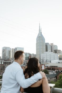 a man and woman standing next to each other in front of a city skyline