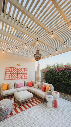 an outdoor living area with couches, tables and lights on the ceiling above it