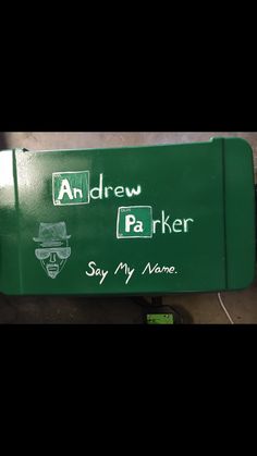 a green box with writing on it that says andrew parker say my name and he is wearing a hat