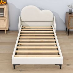 a white bed frame with wooden slats in a living room next to a dresser