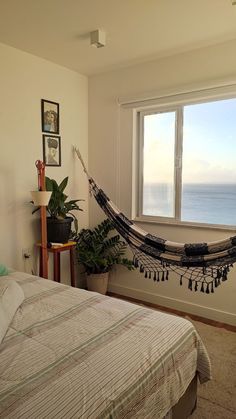 a bedroom with a hammock hanging from the ceiling next to a large window