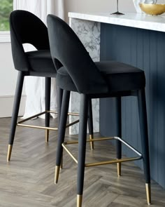 two black and gold bar stools in front of a marble counter with wine glasses on it