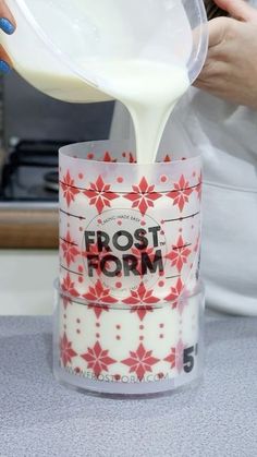 a person pouring milk into a cup on top of a counter