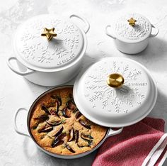 three white dishes with food in them sitting on a table next to red and white napkins